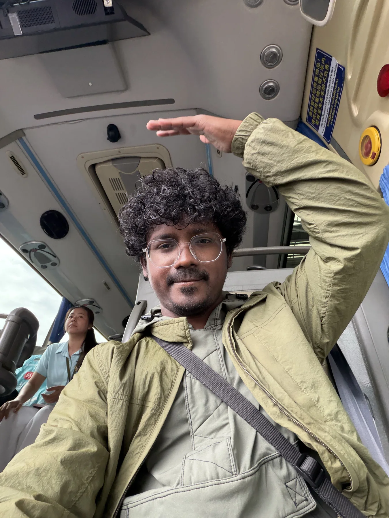 बसमध्ये बसलेले संपादक, एक हात उंचावून डोक्यावर धरलेला